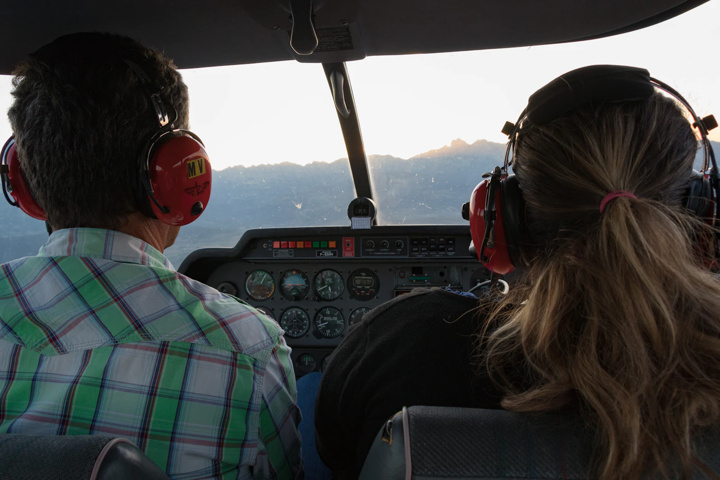 A flight instructor and student pilot wearing headsets in the cockpit of a small airplane