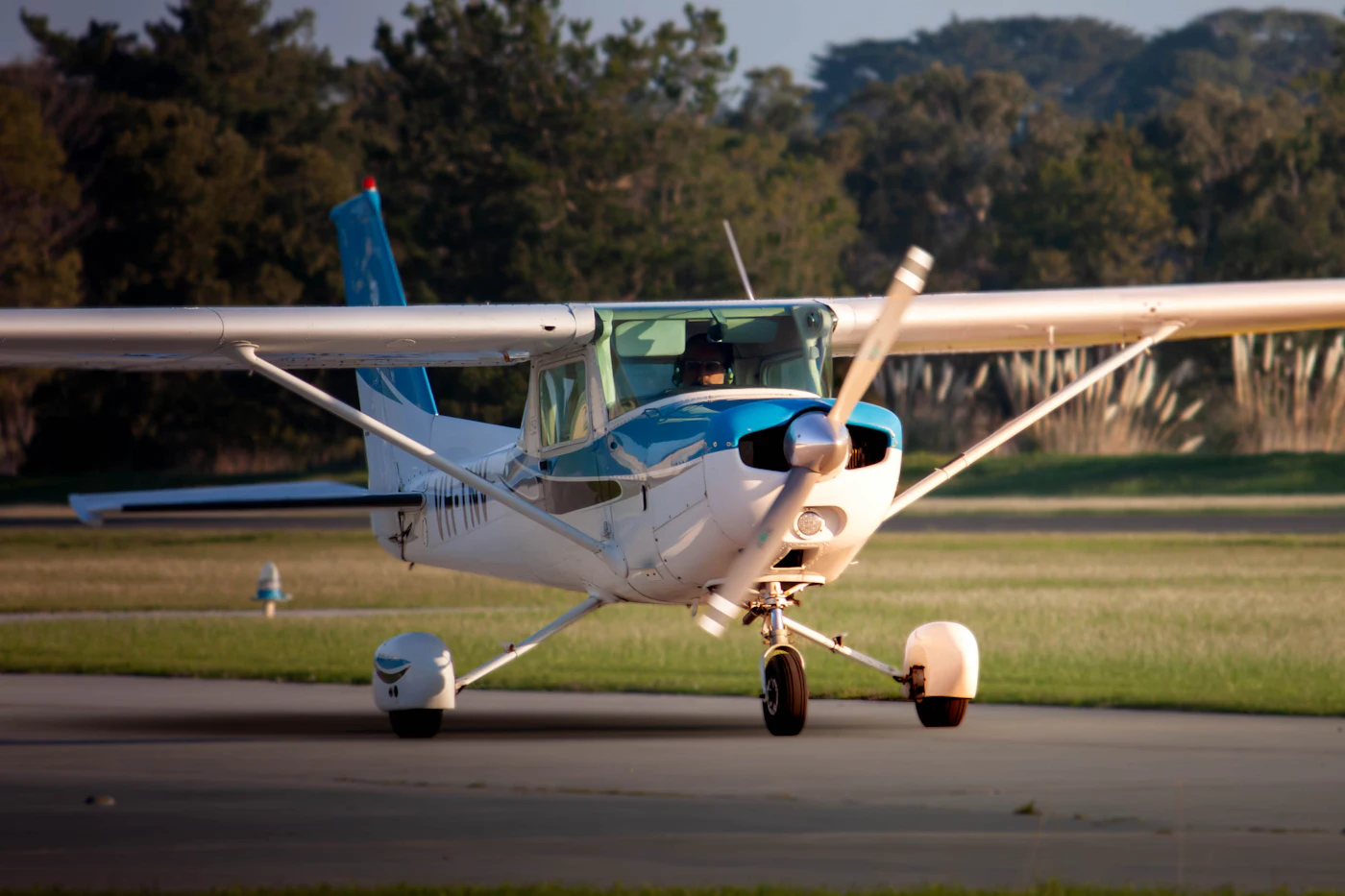A blue and white single-engine trainer taxiing on the runway